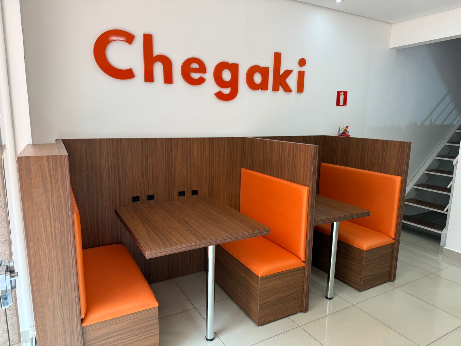Estações de trabalho do coworking da Chegaki com mesas de madeira e assentos laranja
